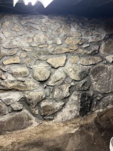 stone foundation wall showing moisture damage and crack repair in basement