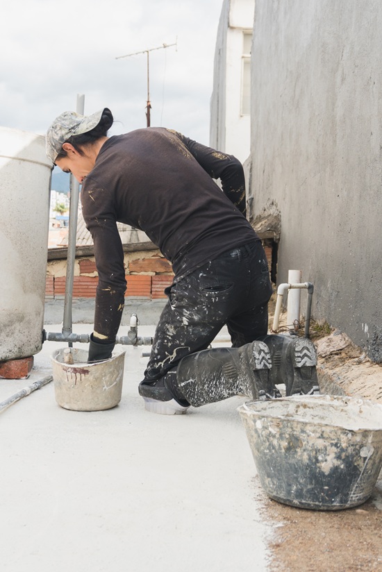 Technician applying waterproof coating during foundation waterproofing repair in New England