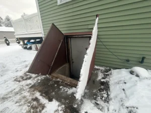 Old rusted bulkhead door with low concrete areaway allowing water intrusion in Derry, NH