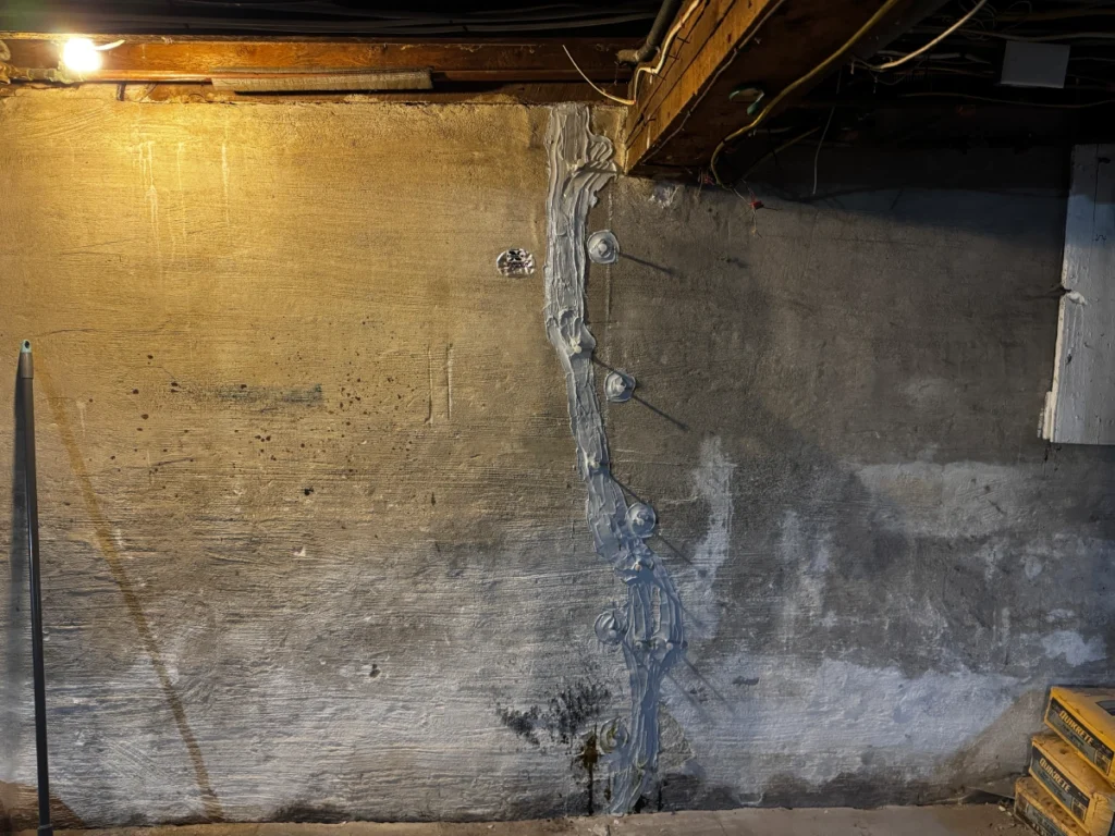 Repaired basement foundation wall crack with epoxy injection ports and structural reinforcement in Auburn, Maine.