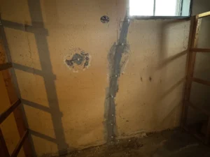 Foundation wall crack repair and tie rod sealing completed in a residential basement in Lowell, MA to stop water intrusion.