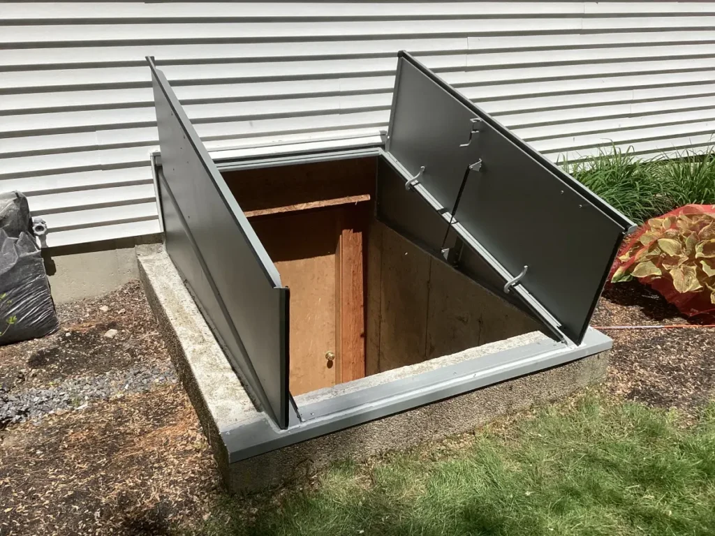 New gray steel bulkhead door installed over a basement entrance in Dover, NH, providing secure and weather-resistant access to the home's basement.