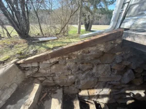 Deteriorated fieldstone foundation wall surrounding an old bulkhead entrance before repointing and bulkhead door replacement in Marlborough MA.