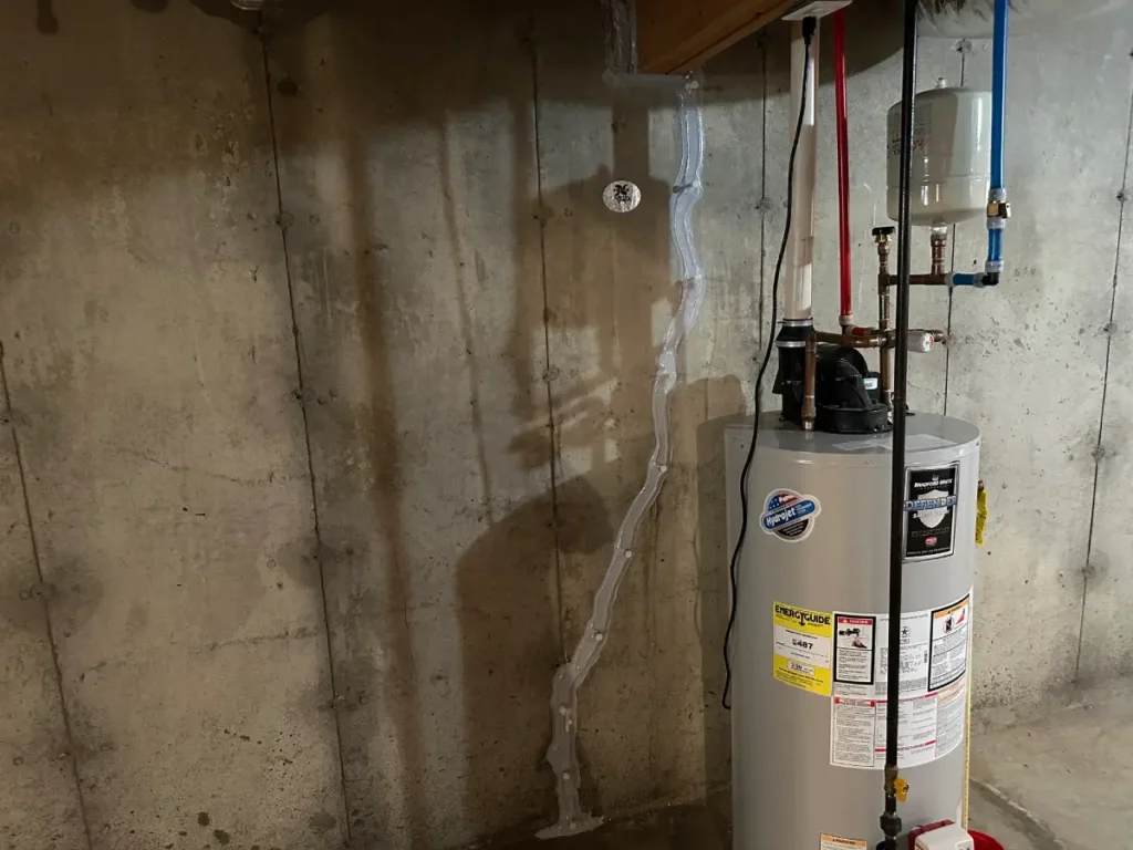 Completed foundation wall crack repair beside a water heater in a Litchfield, NH basement