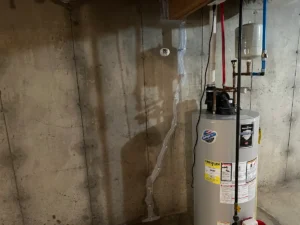 Completed foundation wall crack repair beside a water heater in a Litchfield, NH basement