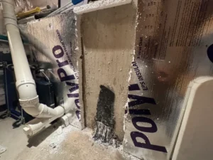 Concrete basement foundation wall with a vertical crack and failed previous sealant repair in Newburyport, MA.